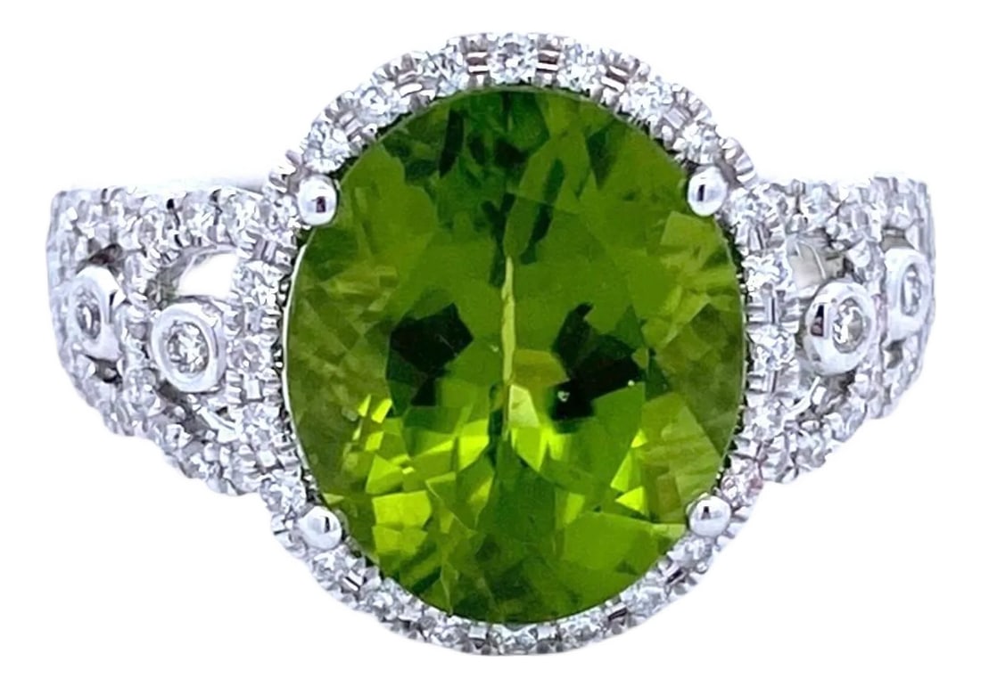 18k White Gold Peridot and Diamond Ring: Crafted in 18K white gold, the ring showcases a striking oval-cut peridot at its center. The vibrant green stone is encircled by brilliant-cut diamonds, and the band is adorned with additional
