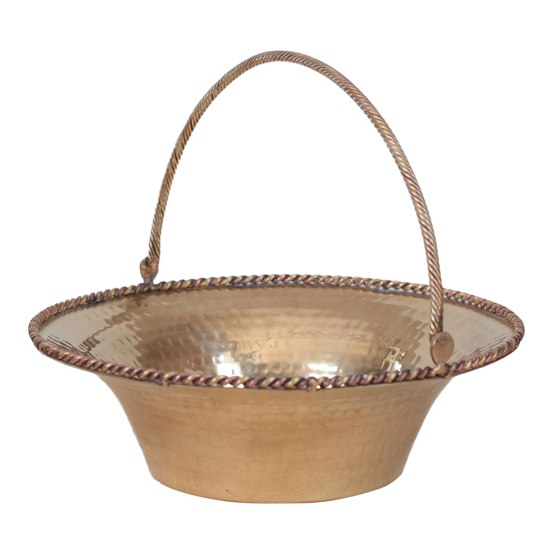 Mid-Century Hammered Brass Basket Bowl With Swing Handle: This mid-century hammered brass basket features a wide, flared bowl, a swing handle of twisted brass rod, and a decorative rope trim along the rim in brass and copper tones. Measuring a substantial 12