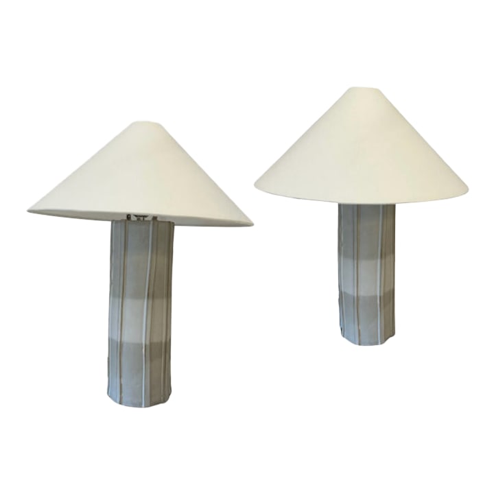 Mid 20th Century Handmade Ceramic Table Lamps by Kaimin Meehan - a Pair: Pair of handmade ceramic table lamps by Kaimin Meehan featuring faceted white ceramic bases and tall pleated shades. The sculptural column bases have a subtle fluted profile with exposed cord exits