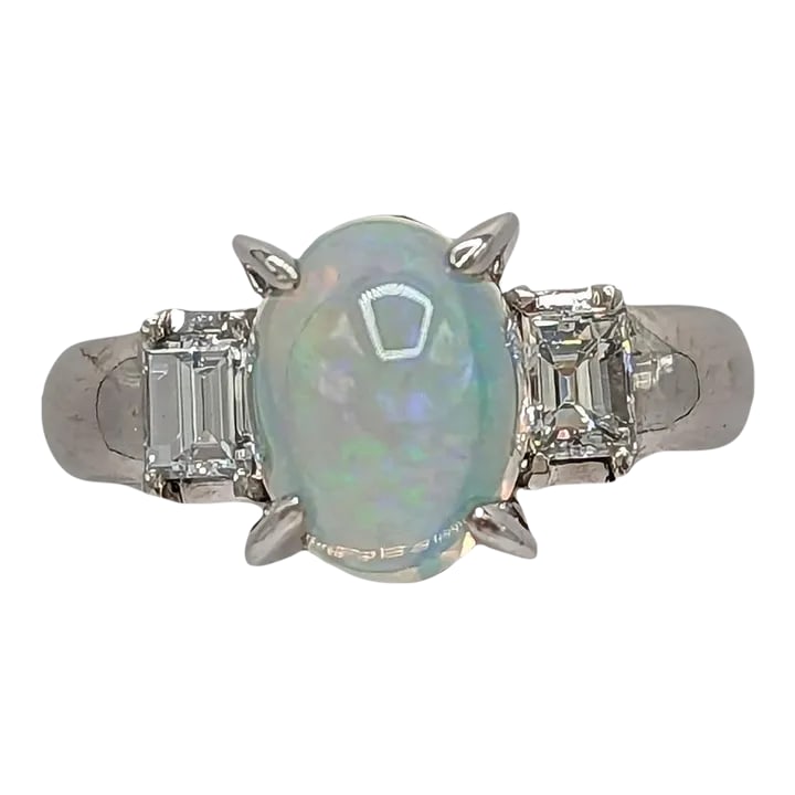 Opal and White Diamond Three Stone Ring in Platinum, size 6.25: Beautiful 3.18 ct. opal oval cabochon with 0.51 ct. white diamond emerald cuts on either side. Handmade in platinum. Ring size 6.25. Metal: Platinum Stone: White Diamond,Opal Stone Cut: Oval Cut