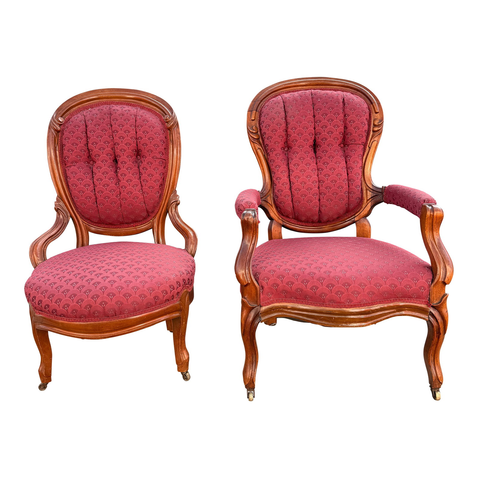 Pair of His/Hers Early 1900s Carved Wood Victorian Parlor Chairs: His and hers set of early 20th Cent. Victorian carved walnut chairs with red and burgundy fan / floral upholstery and braided trim. Likely original horse hair stuffing, front brass casters on both. St