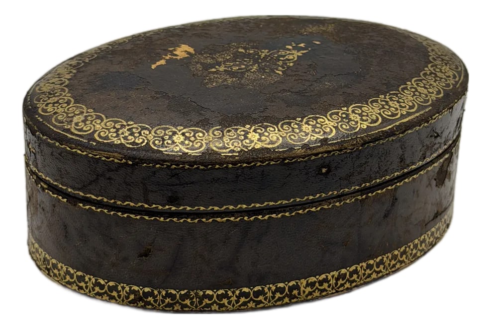 Vintage Italian Florentine Tooled Leather Oval Box: A beautifully aged Italian Florentine leather box, featuring classic gold tooled detailing and a warm, rich patina. The oval shape and intricate gilt patterning highlight traditional Florentine