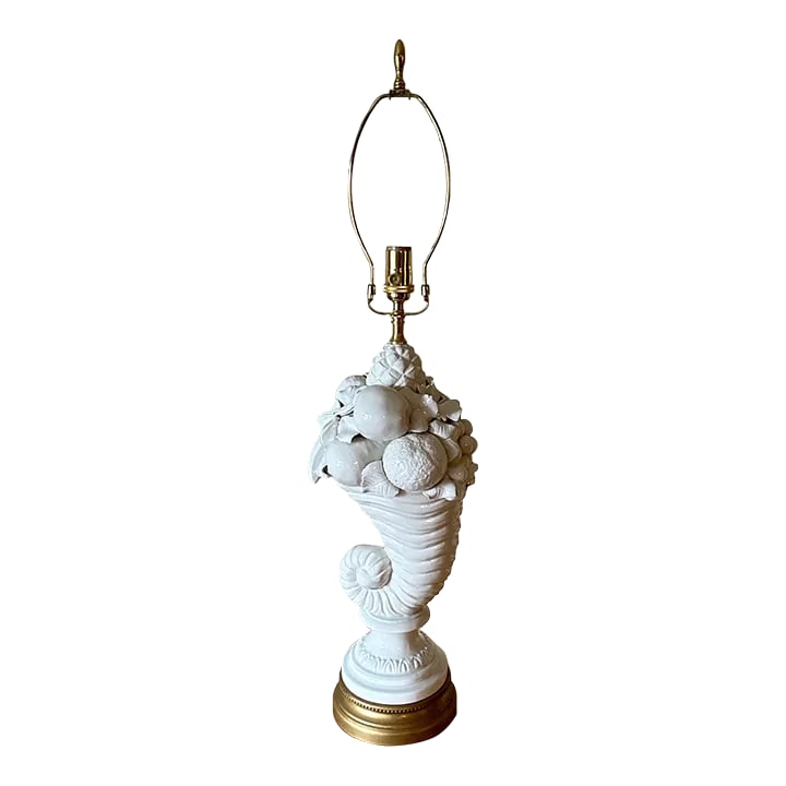 Vintage Mid-Century Italian Cornucopia Topiary Fruit Blanc De Chine White Ceramic Lamp: Vintage cornucopia topiary lamp from the mid-20th century. A white Italian made ceramic lamp is seated on a gold painted metal base and is topped with a brass neck, harp, socket and finial. The lamp