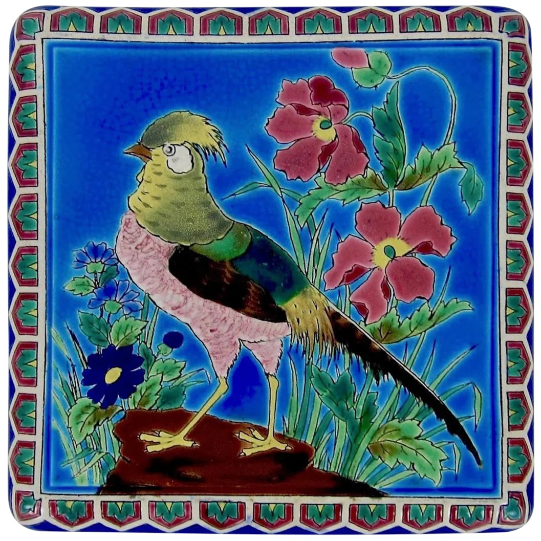 Antique French Emaux De Longwy Stand or Trivet With Cloisonne Style Bird Decor: An antique French faience stand or trivet from the Emaux de Longwy art pottery workshop in France. The decorative ceramic platter rests on four feet and can be displayed on a tabletop or desk. The und