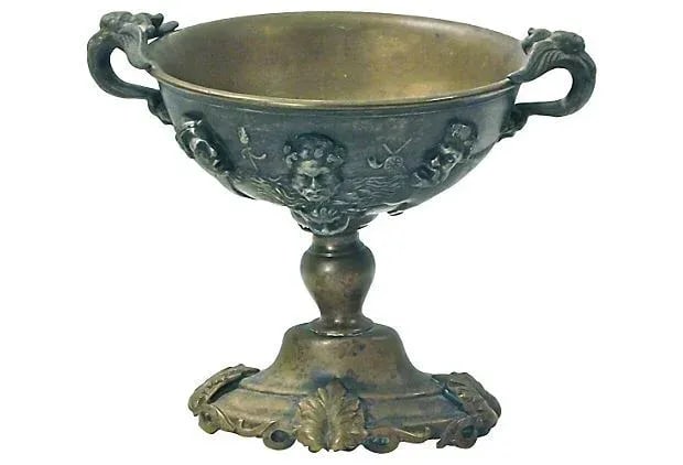 Antique Italian Brass and Bronze Goblet: This antique, 19th century Italian, brass and bronze goblet has aryatid handles and a warrior faces design on the underside of bowl. The base features an acanthus leaf design. No maker's mark.