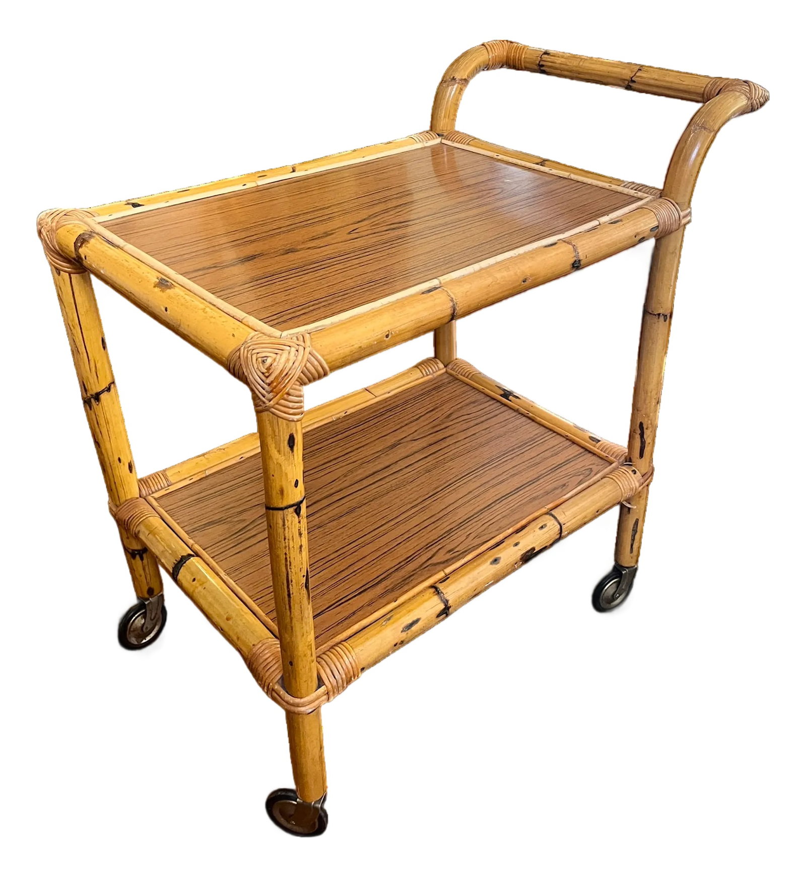 1960s Burnt Bamboo & Rattan Wrapped Two-Tier Drinks or Bar Cart on Casters: Chic 1960s drinks cart crafted in faux bamboo with hand-wrapped rattan joinery details and warm oak-grain laminate shelves. The sculptural bent bamboo-form handle and petite proportions give this