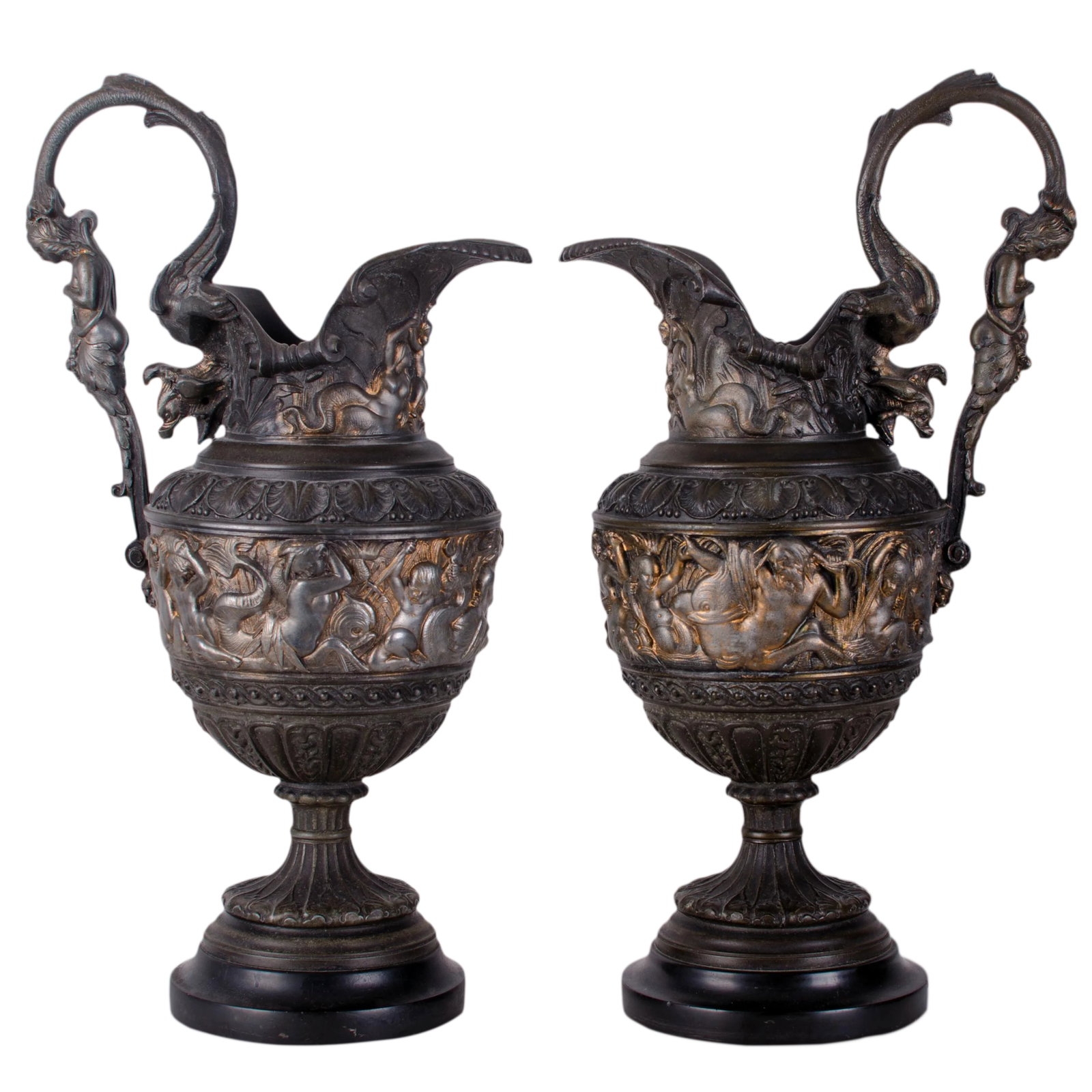Antique Renaissance Revival Triton Ewers: Pair of french renaissance revival ewers depicting tritons and nymphs. Nymphs depicted lifting child under spout. Some remaining gilding. Metal composition mounted on black stone bases. Condition: