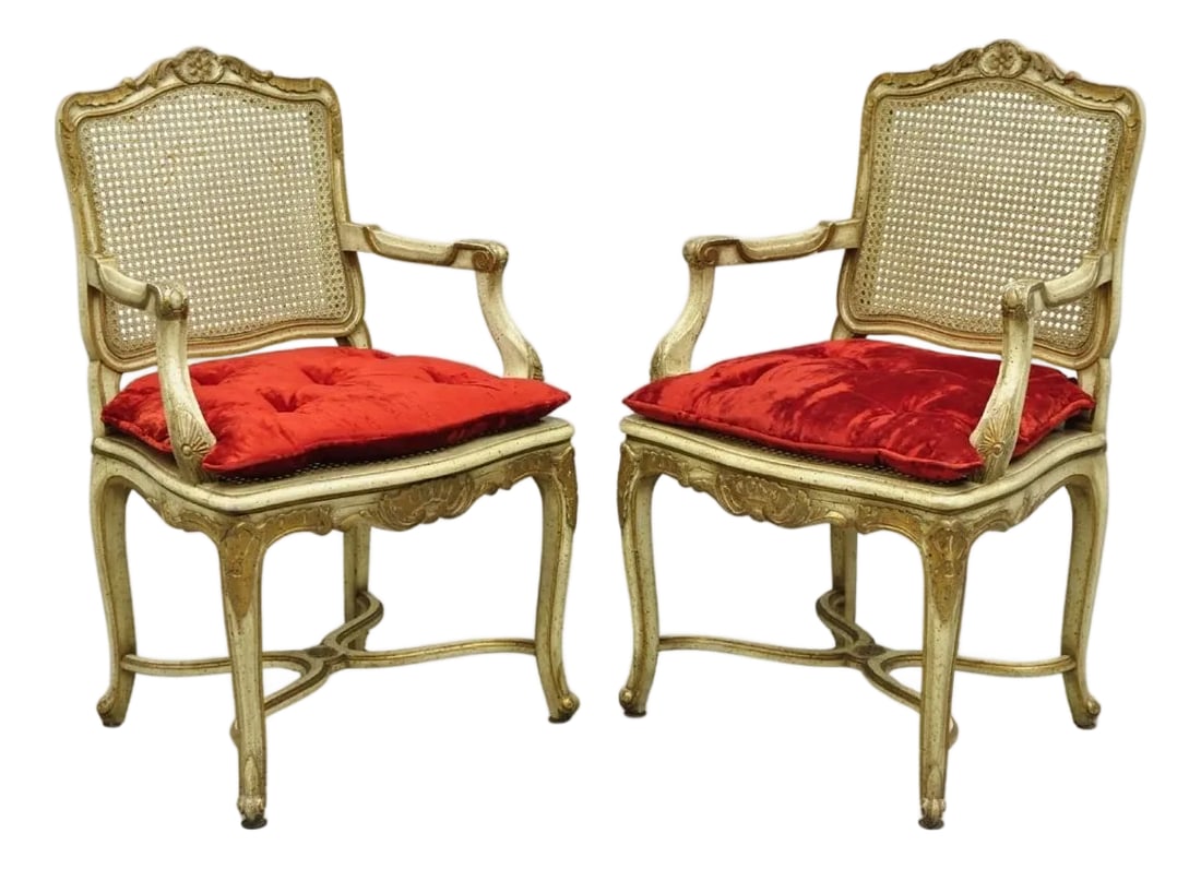 Vintage French Louis XV Style Cream Painted Carved Wood Cane Arm Chairs - A Pair: Vintage French Louis XV Style Cream Distress Painted Carved Wood Cane Back and Seat Arm Chairs with Red Loose Cushions - a Pair. Circa Mid 20th Century. Measurements: 38" H x 24" W x 21" D x 19" Seat 