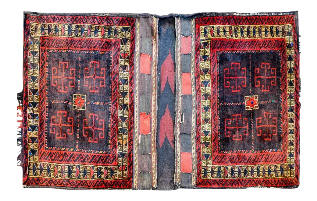 Early 20th Century Baluch Saddle Bag: A fantastic early 20th century Persian Baluch saddle bag with a beautiful woven geometric pattern woven in brown and crimson wool, flanked by a geometric border of red, gold, and brown wool.