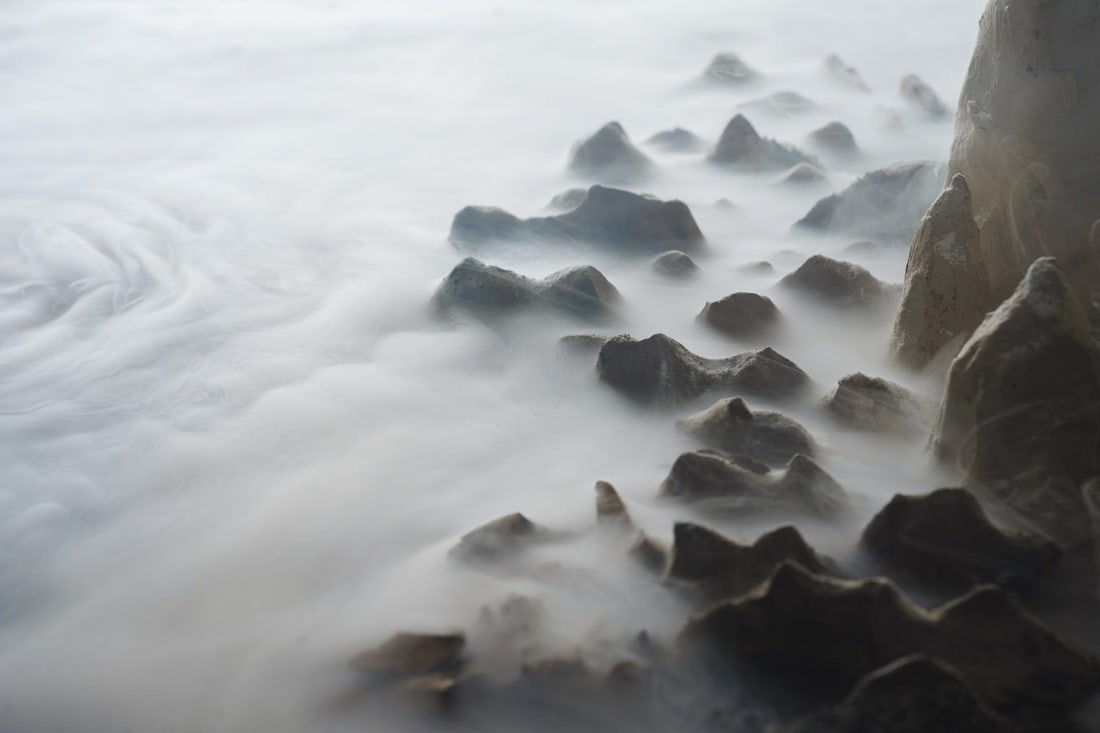 Western Shore by Jenya Chernoff | Constructed diorama and giclee print of a coastal scene: This constructed diorama captures the serene beauty of a western shore, featuring intricate textures created from clay, sand, and coffee grounds. The gentle waves flow over the rugged rocks, evoking