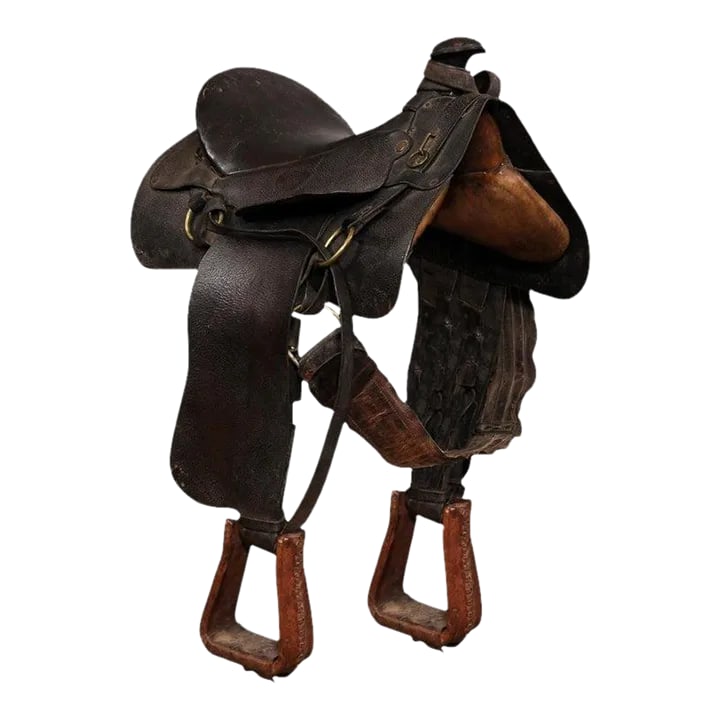 Vintage American Western Style Leather Saddle with Weathered Patina: An American Western style leather saddle from the 20th century, with dark brown/black seat, jockey, fender, horn and lighter brown stirrups. Handcrafted in America during the 20th century, this