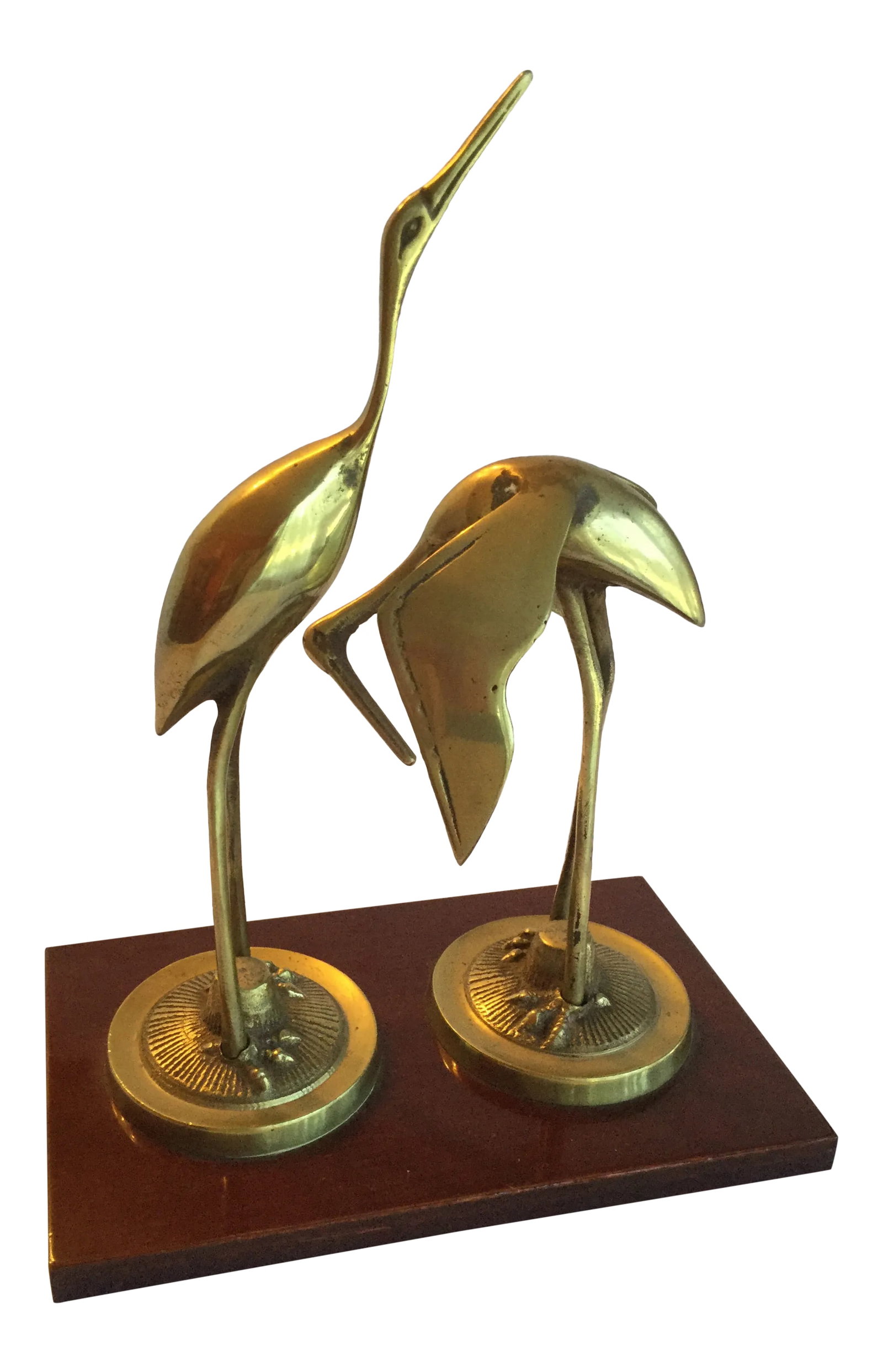 Vintage Brass Cranes Figurine: Two brass cranes or egrets face each other, their long legs and long necks and beaks showing off the elegant graceful lines of their wings and bodies. They are mounted on a simple mahogany colored