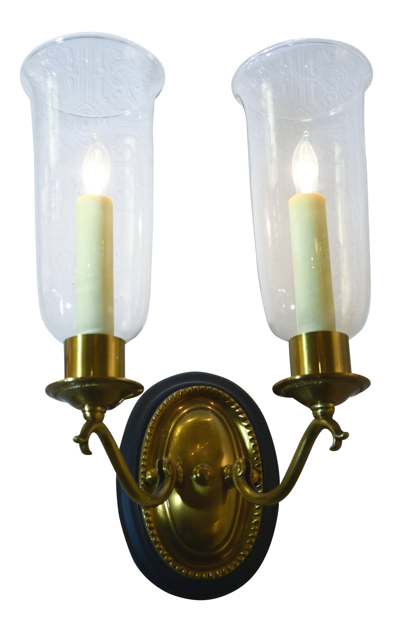 Two-Light Chimney Sconce: Solid brass sconce in an antique brass finish with glass chimneys is mounted on a wood backplate. Two candelabra sockets each hold a 60-watt max. bulb. Condition: Imperfections: No Imperfections Condi