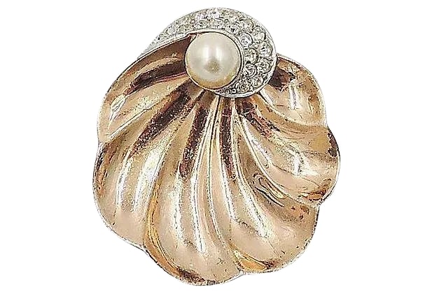 Vintage Signed Boucher Goldtone Shell Fur Clip, 1947: Gold-plated sterling shell-shaped fur clip set with a resin faux-pearl and pave rhinestones. Marked "Sterling" with Boucher's phrygian cap mark and inventory number "2253." Patented in 1947. Measures: