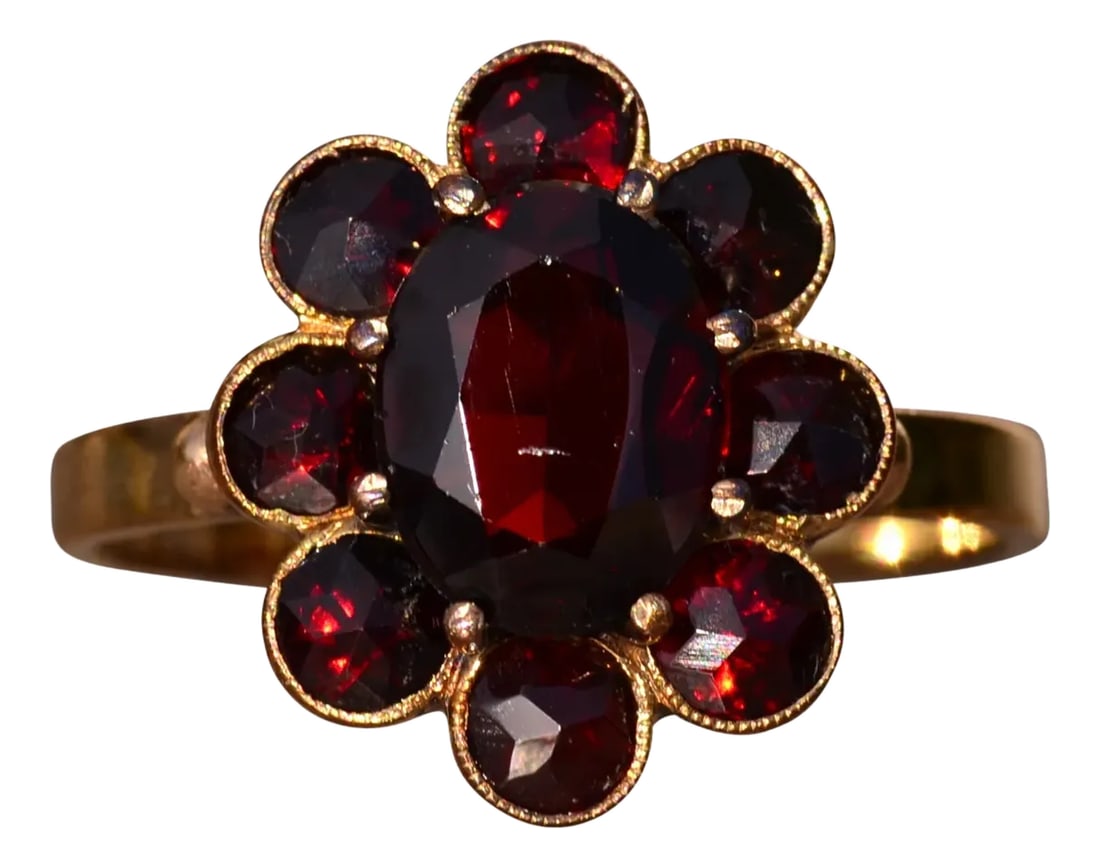 The St Augustine: Bohemian Rose Cut Garnet Ring in Yellow Gold: The St Augustine: Bohemian Rose Cut Garnet Ring in Yellow Gold. The ring centers on a oval brilliant cut natural garnet center stone with halo of rose cut garnets surrounding the center. The ring is