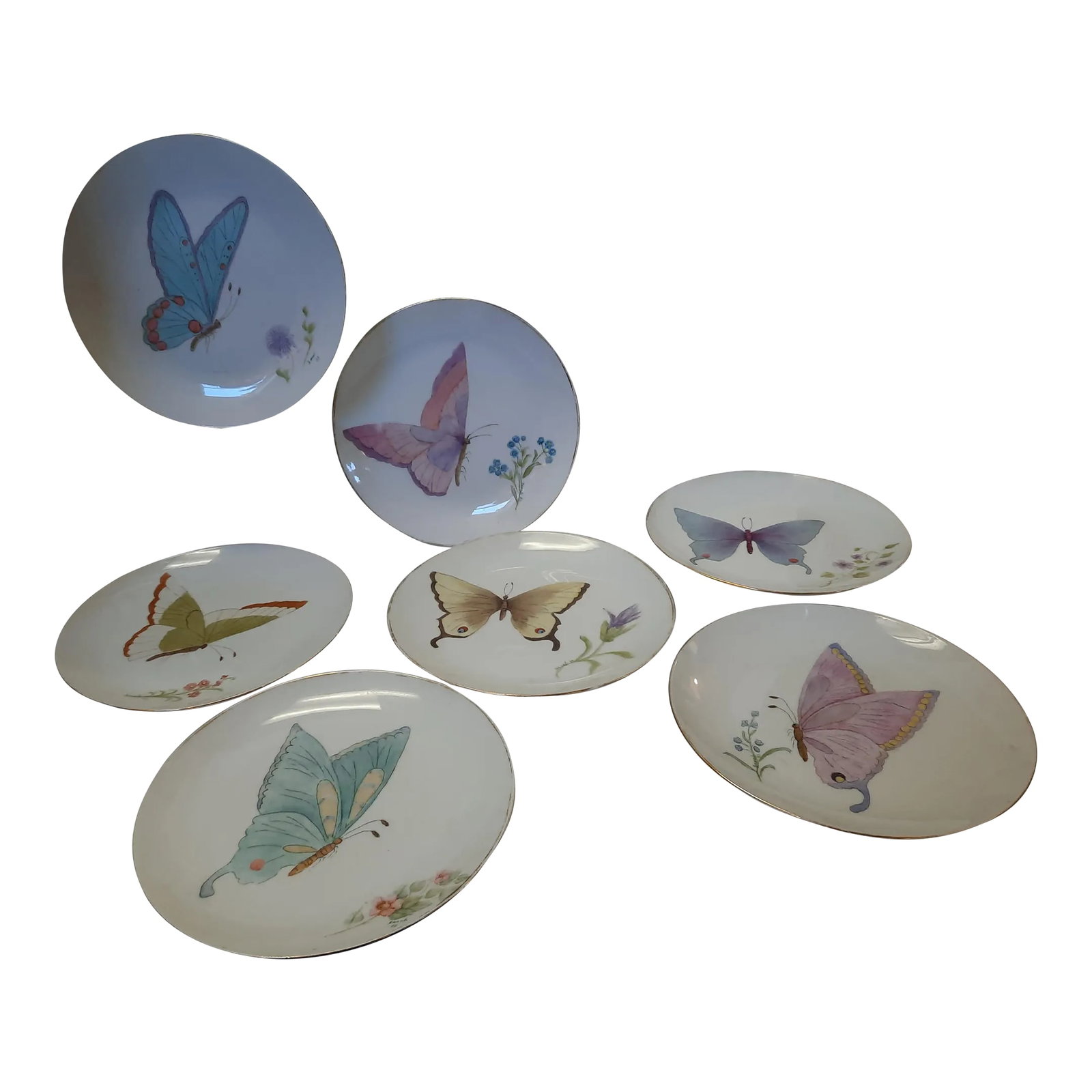 1980s Painted Plates - Set of 7: Set of 7 Hand-Painted vintage porcelain plates. Each plate is painted with a different butterfly design. They are signed "Sarah 83" . The 24ct. gold rim is worn off on almost all of the plates rims.