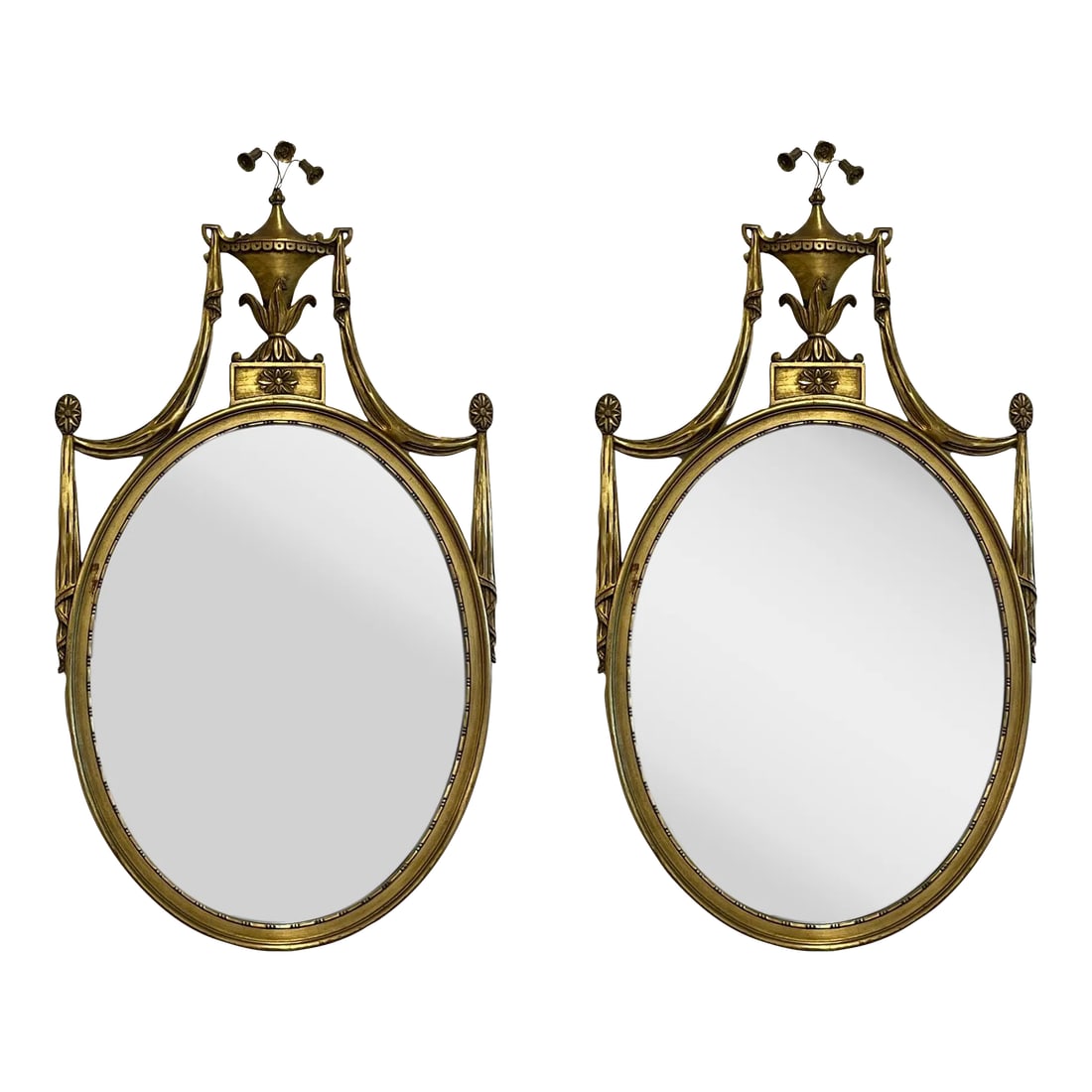 Pair of Adams Style Giltwood Wall Mirrors, Console or Commode Mirrors: Pair of Adams Style Giltwood Wall Mirrors, Console or Commode Mirrors Each mirror having an oval frame flaked by swag carving terminating in an urn and scroll floral design. A classic Adam style crest