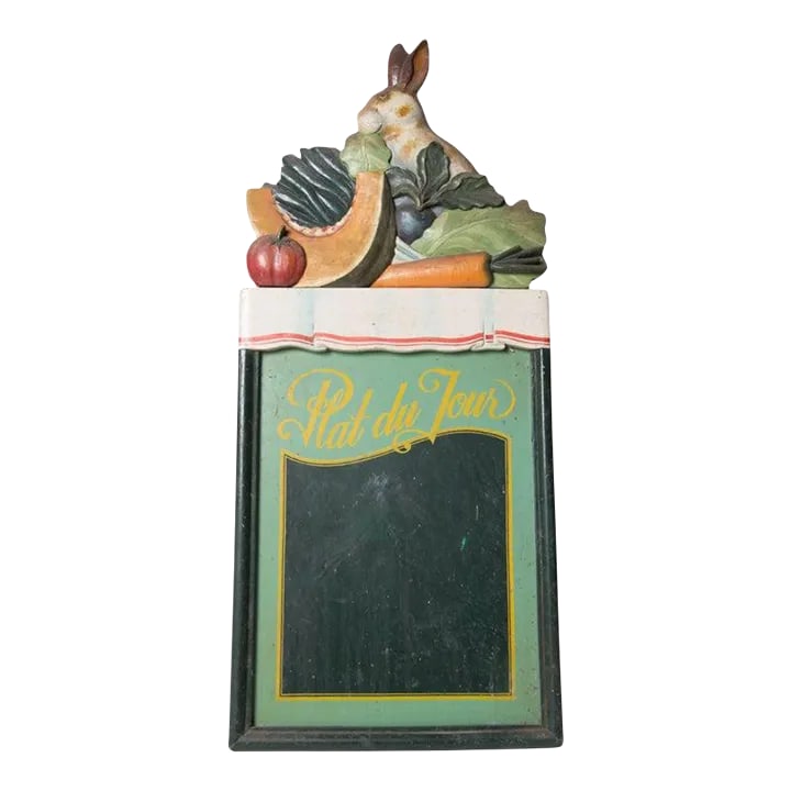 1970s Plat Du Jour Rabbit Chalk Board: A charming Plat du Jour Rabbit chalk board. The rabbit sits with a cluster of colorful fruits and vegetable atop a tablecloth covered table all above the plat du jour chalk board. The sign is carved