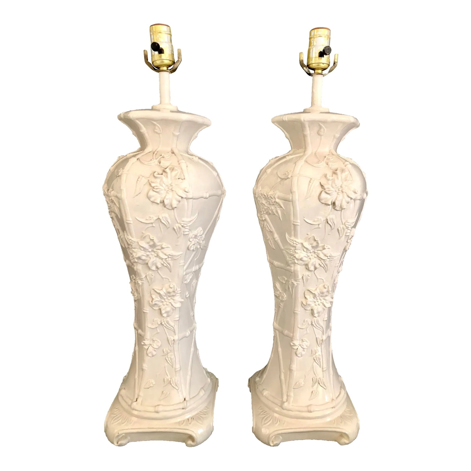 Pair of Chinoiserie Glazed Porcelain Lamps With Faux Bamboo and Floral Relief Accents: These stunning Hollywood Regency style tall porcelain table lamps are expertly crafted in a high relief floral botanical design with a faux bamboo fretwork backdrop and a Ming style footed base. The