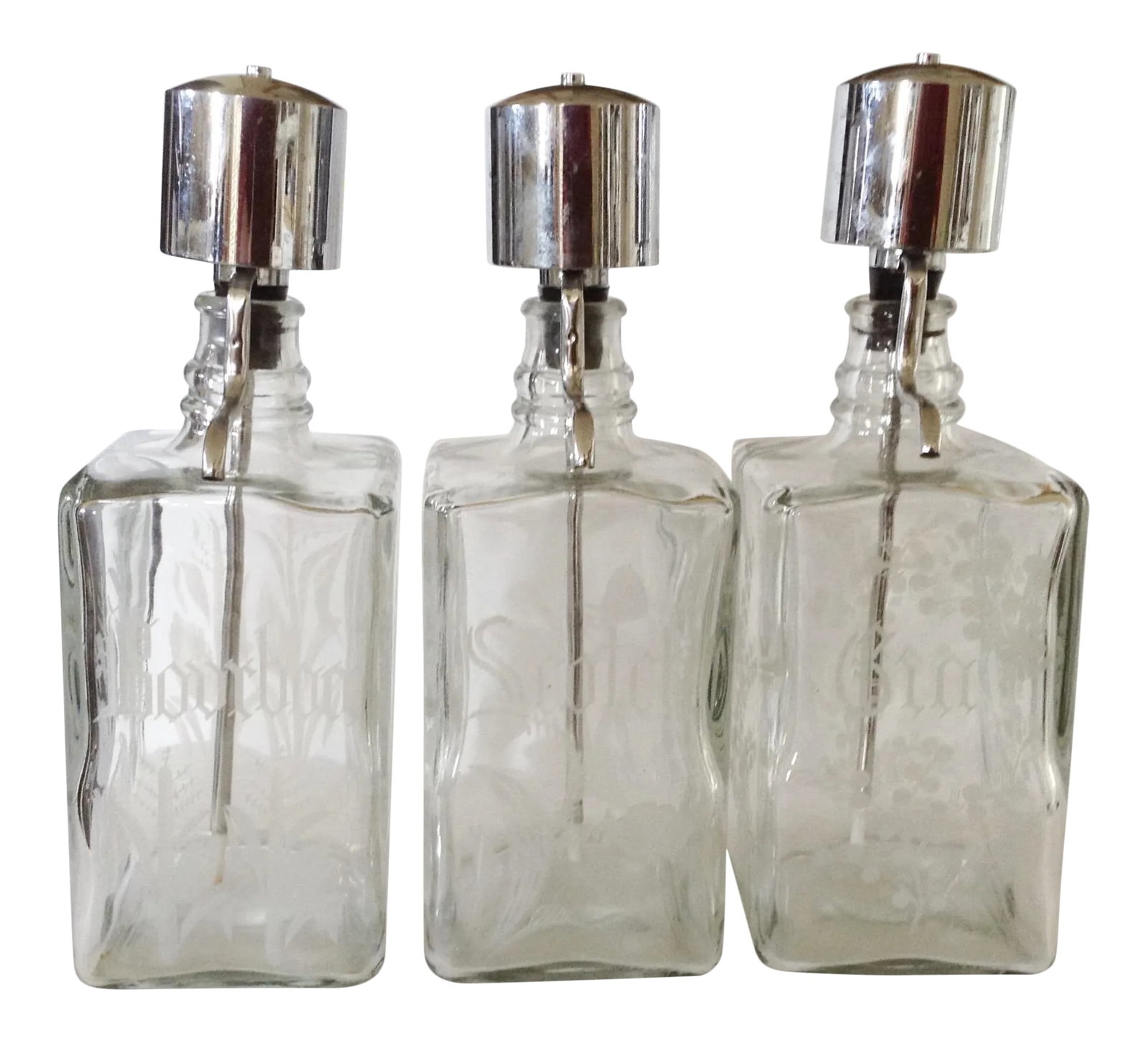 Gin/Scotch/Bourbon Liquor Bar Decanters - Set of 3: Three liquor decanters including bourbon, scotch and gin, fashioned in glass that has each been etched with the plant of it's origin. Each topped with a silver metal pump dispenser and rubber stopper