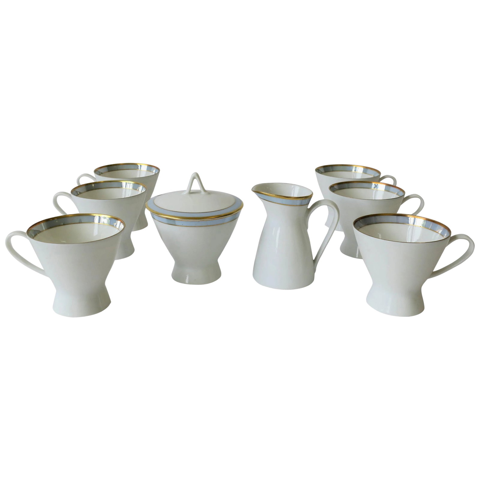 Midcentury Modern White Porcelain Coffee or Tea Set by Rosenthal: A beautiful Mid-Century Modern porcelain coffee or tea cup set, with creamer and sugar, in white with touches of gold and blue. Set includes six cups, one creamer and one sugar bowl with lid, by
