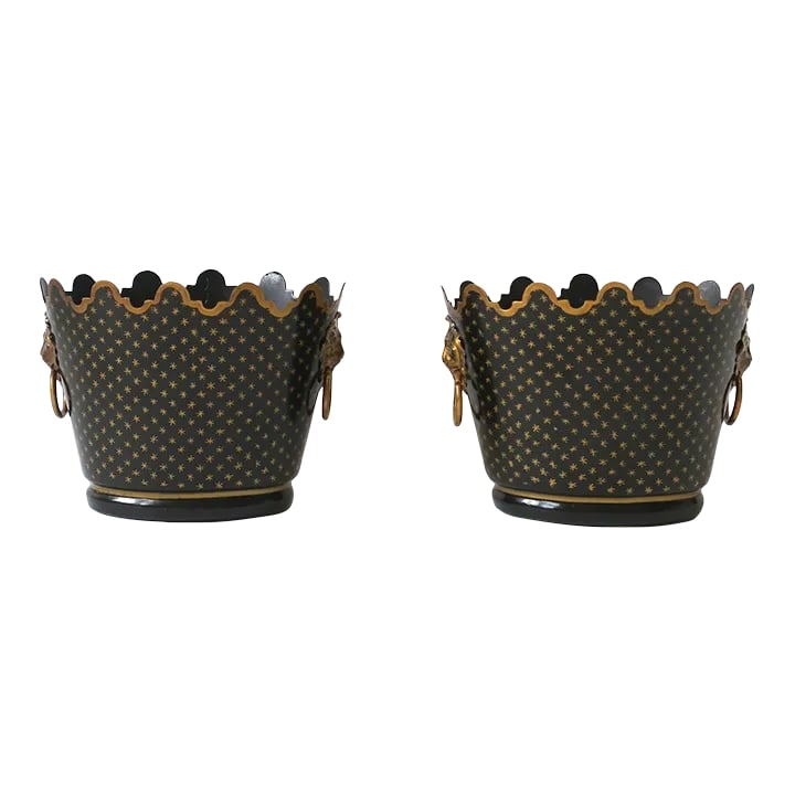 Italian Black & Gold Tole Cachepot Jardiniere Lion Head Planters, Pair: A pair of Italian black and gold metal tole cachepot jardiniere planters in the Regency style, circa late 20th century, Italy. Pair are oval in shape with gold trimmed scalloped edge, black ground