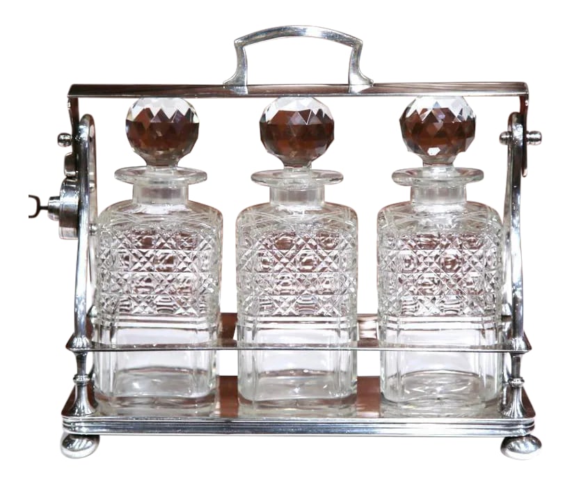 19th Century English Silver Plated 3-Carafe Tantalus With Lock Mechanism: Entertain in style with this beautifully crafted, antique Tantalus from England. Crafted, circa 1860, the bar accessory is made of three cut-glass carafes with decorative stoppers. The top handle can