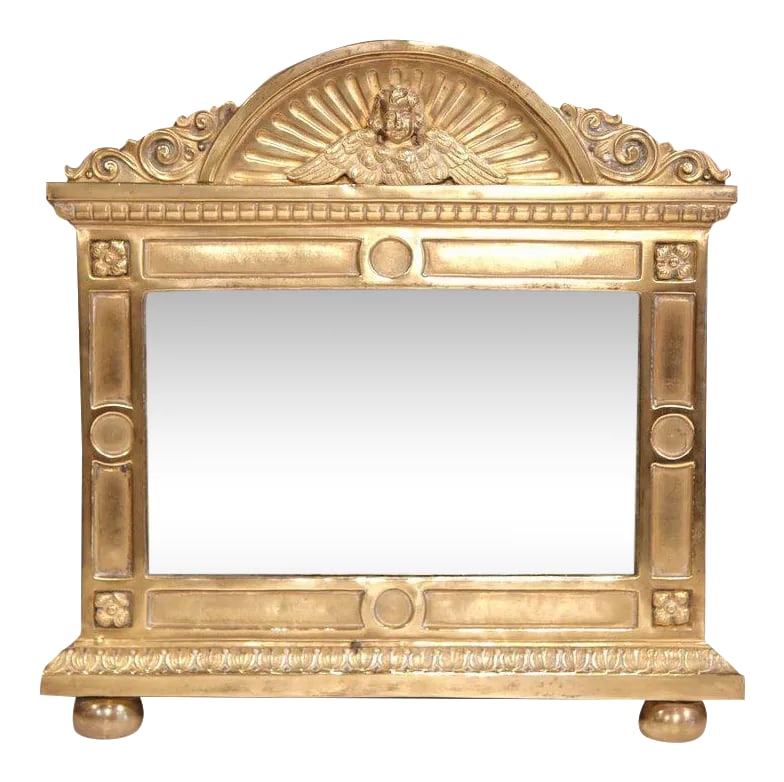 19th Century French Repousse Brass Wall Mirror With Cherub Crest: Decorate a powder room, entry, or intimate wall space with this charming antique French repousse brass mirror, crafted circa 1880. The piece features a refined architectural frame topped with an
