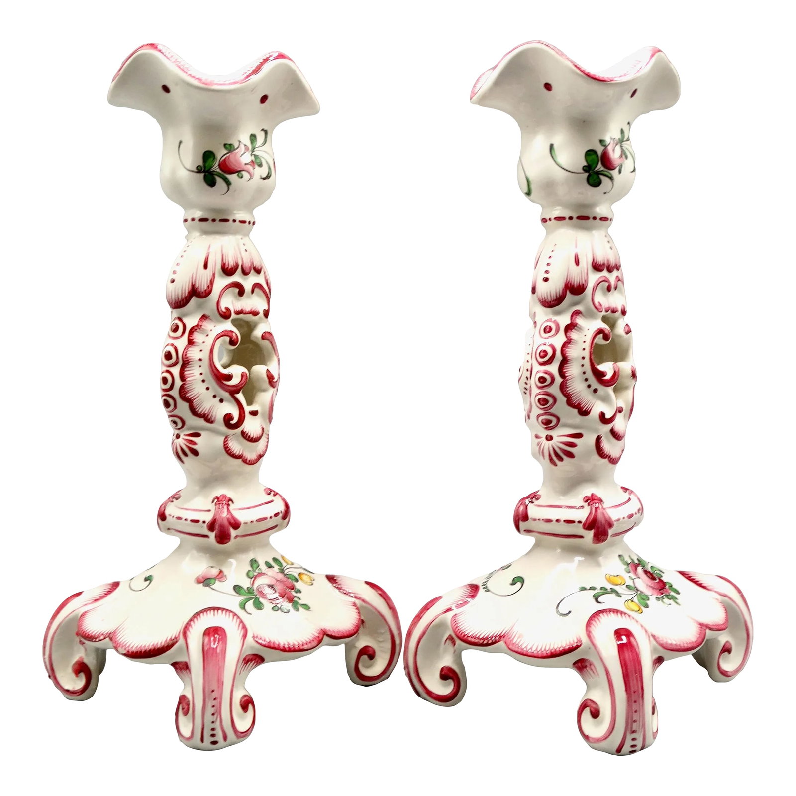 Early French Hand Painted Faience Candlesticks, a Pair: A lovely early 20th-Century pair of French faience candle holders. They are hand painted and decorated in rose pink colors with a floral motif at the base and raised on pretty scroll legs. Marked on