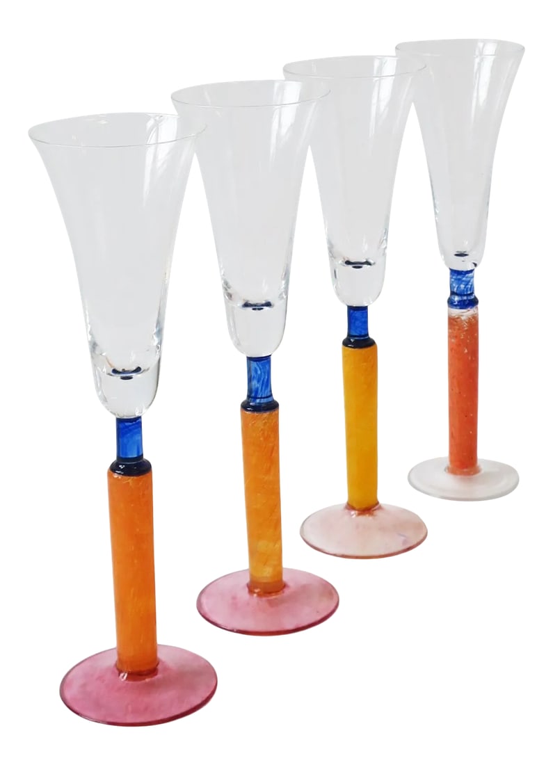 1990s Orange Art Glass Champagne Flute Glasses, Set of 4: A beautiful set of four (4) Postmodern orange art glass Champagne flute glasses, circa 1990s, Europe. In the style of Kosta Boda, Sweden. Colors include: orange, pink, and blue. A beautiful set for
