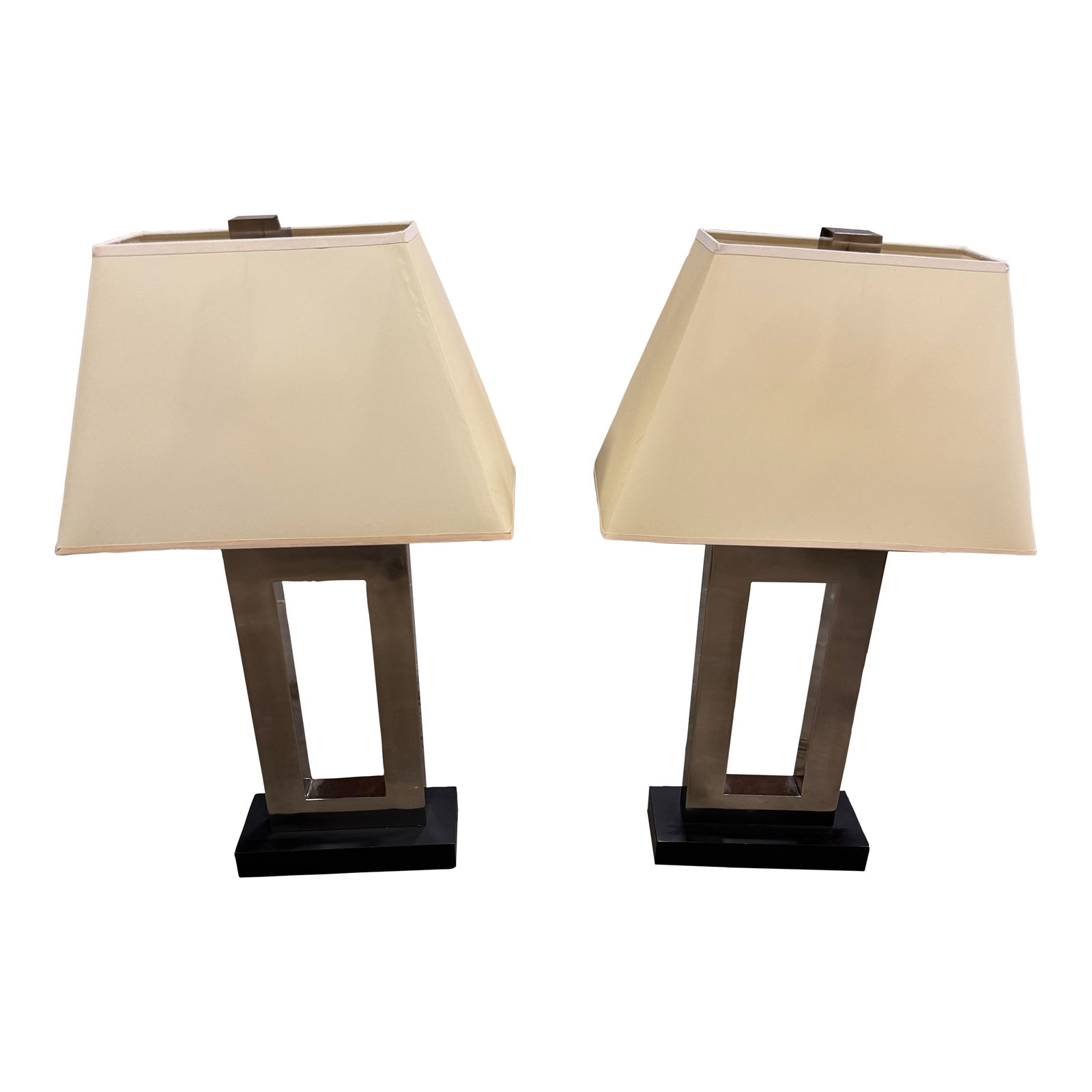 Pair of Modern Brushed Robert Abbey Style Metal Open-Frame Table Lamps: A sleek and sculptural pair of modern table lamps featuring a minimalist open-frame design in brushed metal. Anchored on black rectangular bases, these lamps offer a striking architectural