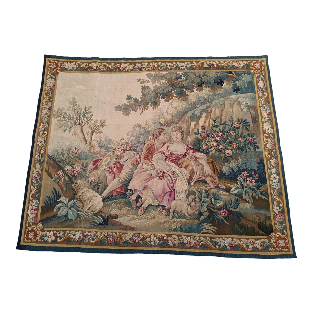 19th Century French Aubusson Tapestry: Late 19th Century French Tapestry featuring a romantic scene with a courting couple, sheep, and a lush countryside setting, all framed by an ornate floral border. The soft, muted palette and