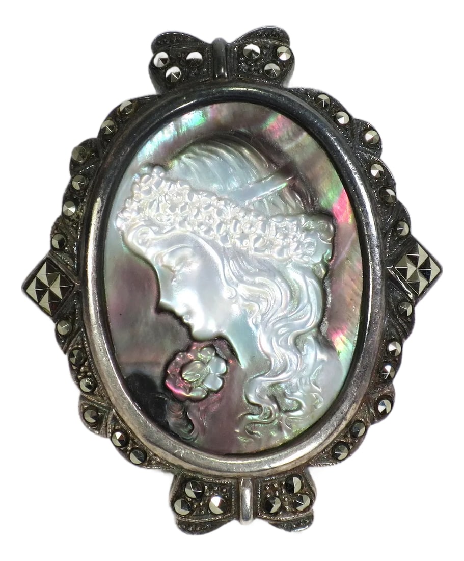 Antique Edwardian Sterling Abalone Marcasite Cameo Brooch 1910s: Antique Edwardian sterling and carved abalone cameo brooch with marcasites. Exquisitely carved cameo of a maiden with flowing tresses bound by a garland, with a flower on her shoulder. The frame is