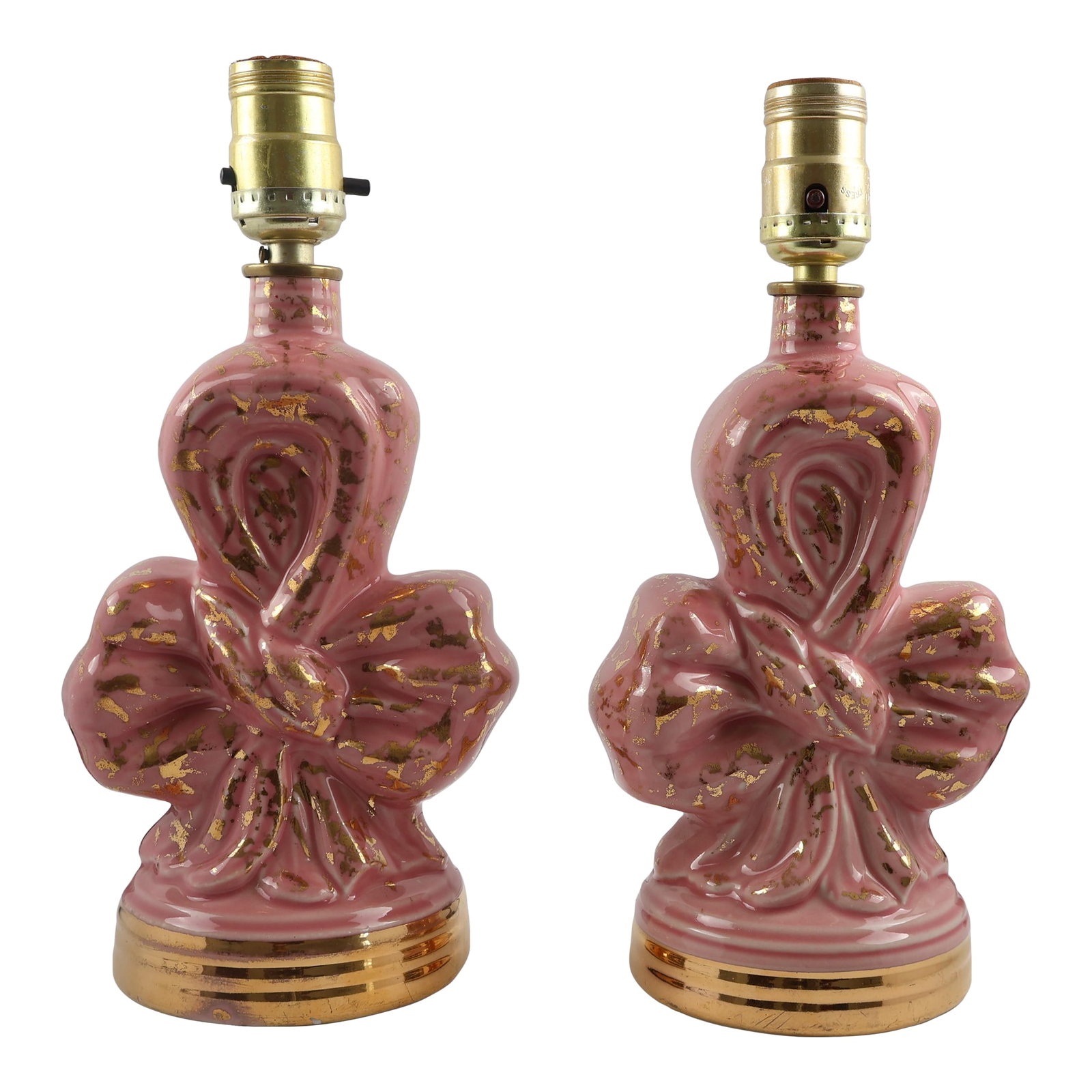 Vintage Pink Ceramic Bow Lamps With Gold Accents Hollywood Regency, 12 In - a Pair: A striking pair of vintage ceramic table lamps in a sculptural bow form, finished in glossy rose pink with scattered gold accents. The bases are trimmed in polished gilt, giving the set a glamorous Ho