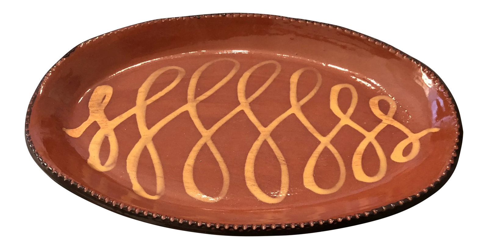 Redware Platter With Yellow Slip and Pie Crust Edge: This platter is 13.5 in L X 8.5 in W. It has yellow and black slip ware decoration in the center of the platter and a pie crust edge. The mark on the back reads By Cazan Cabin Craft Pottery, OHIO. It
