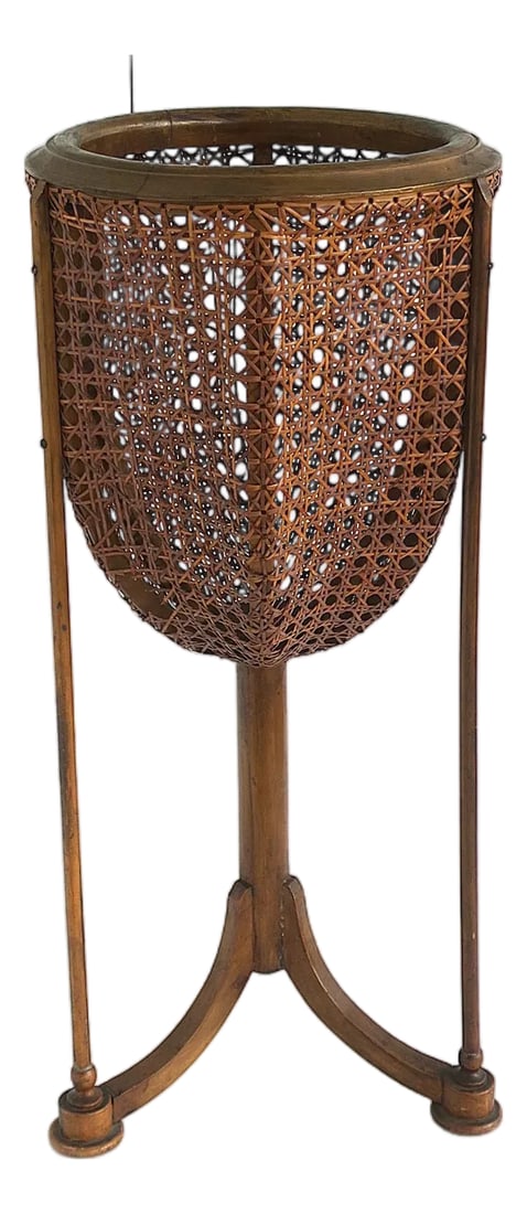 Wicker Cane Plant Stand, Circa Mid-20th Century: A vintage wicker cane plantstand with tri-pod base/legs, mid-20th century, circa 1960s-1970s. Piece may be Italian; however, it is unmarked. Plantstand has a round funnel-like cane basket supported by