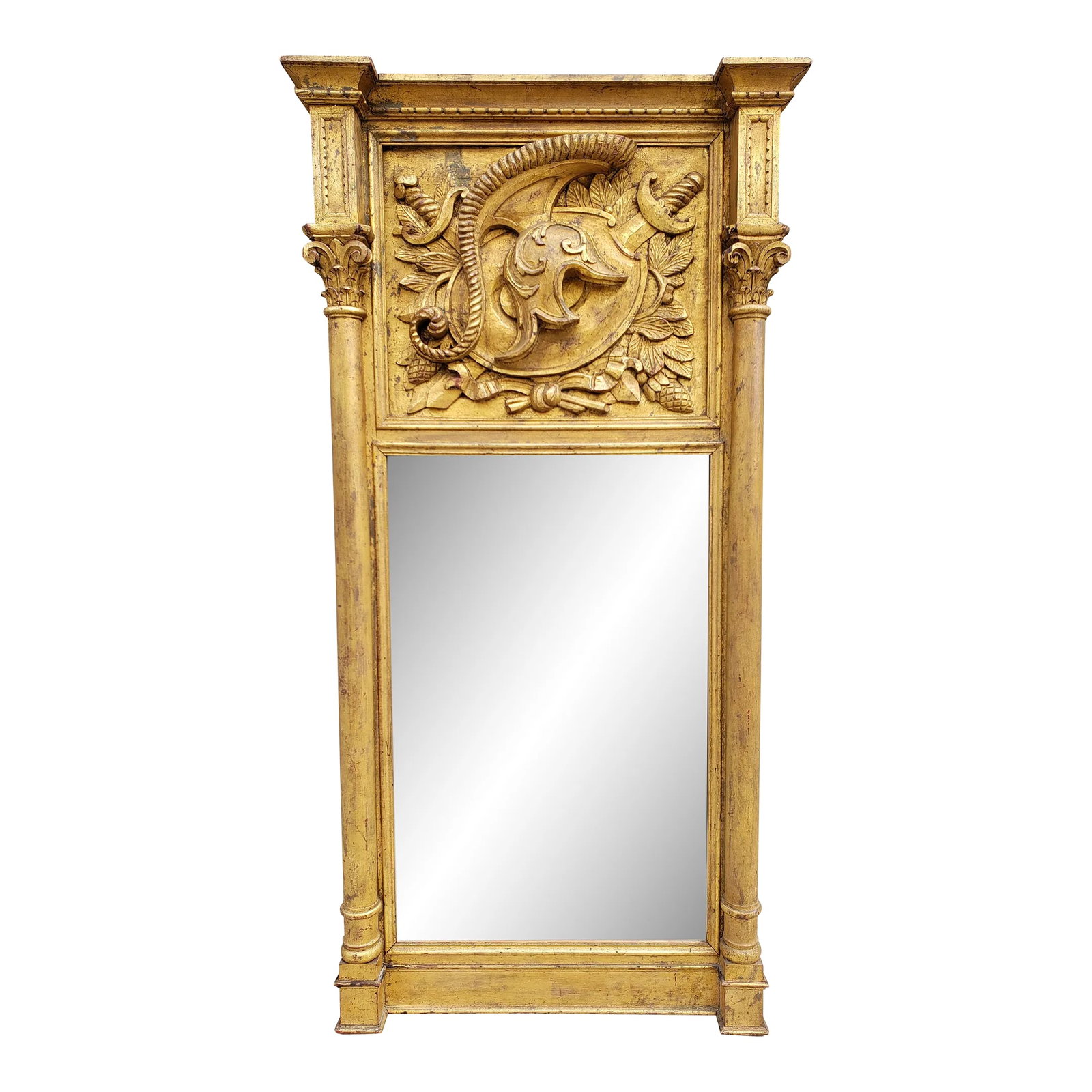 Vintage Carved Giltwood Armory Motif Mirror: Vintage large Italian carved giltwood armory motif mirror featuring a top panel with the subject of a helmet with swords, leaves and pine cones framed by large columns. The stunning mirror will