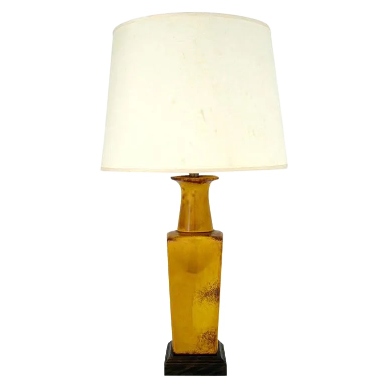 Saffron Glazed Vase Form Table Lamp by Frederick Cooper: This early Fredrick Cooper table lamp features an incredibly vivid red glaze over saffron vase form ceramic body with a carved wood plinth base. Sold sans shade. Condition: Alterations: Original