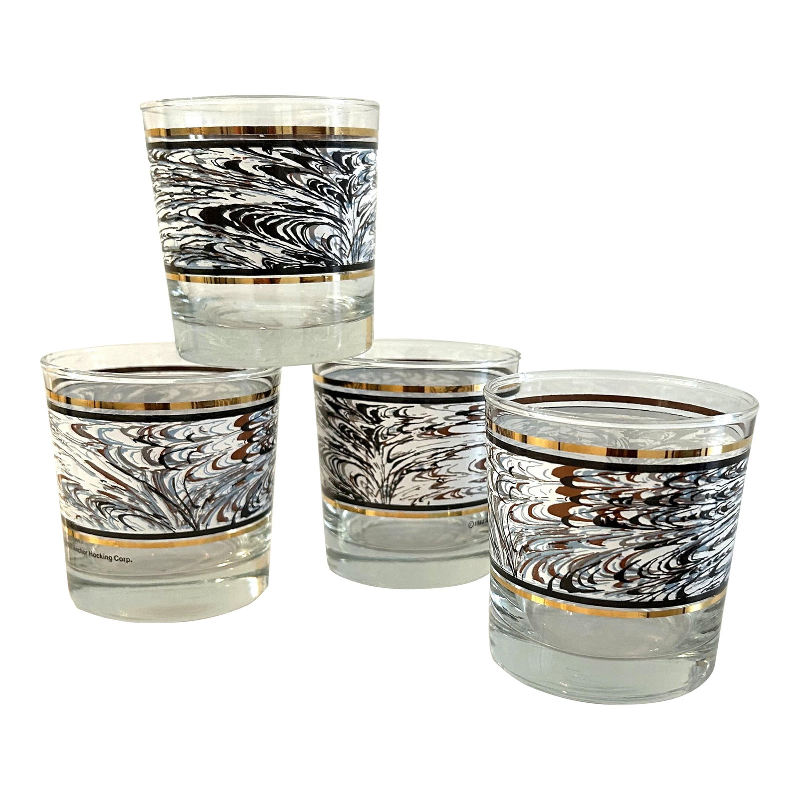 1980s Anchor Hocking Swirl Lowball Glasses, Set of 4: Cool set of four 1980's Anchor Hocking lowball glasses featuring a wide band in a swirl design in shades of white, blue, black, and brown with band of 24K embellishment flanking each side. Each glass