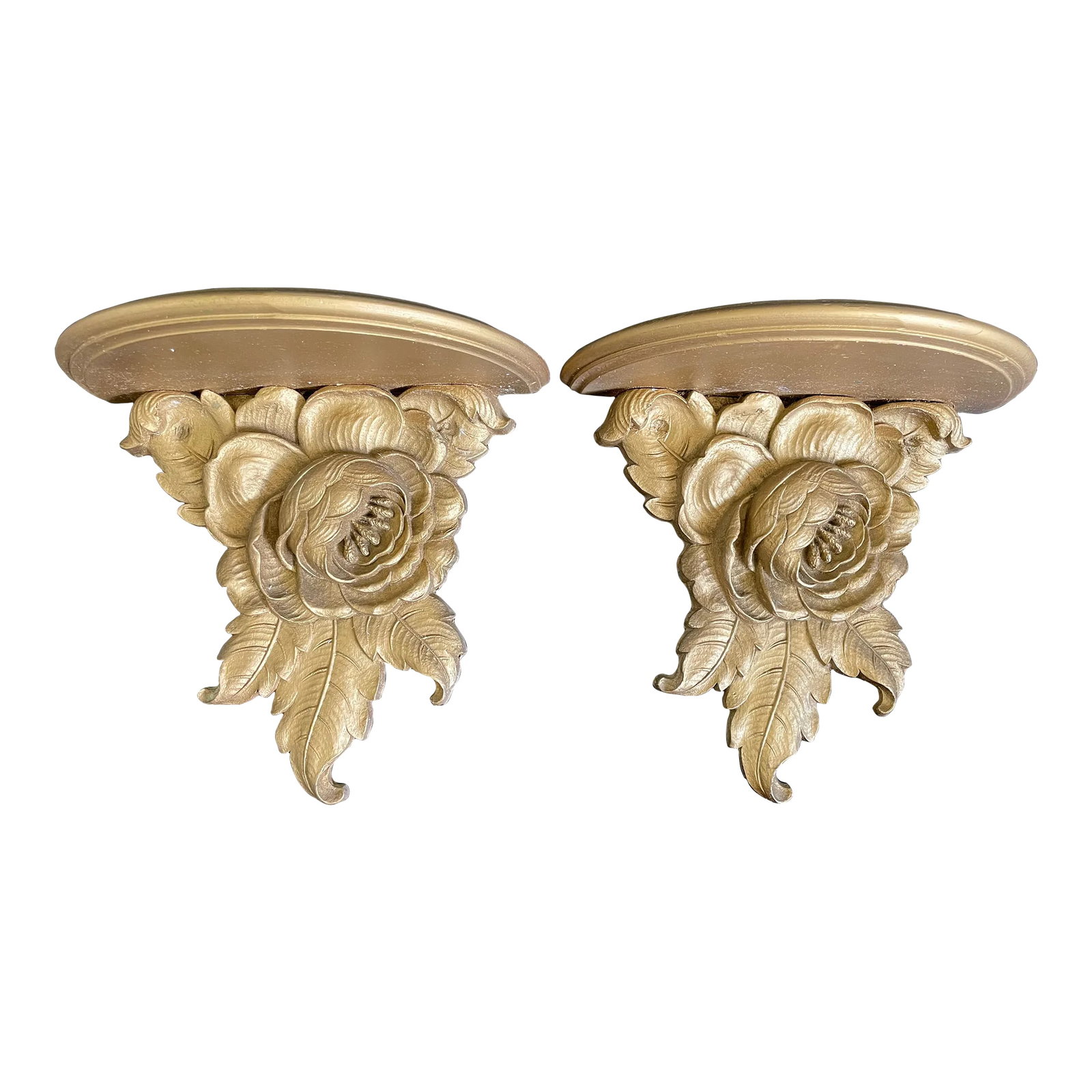 Syroco Wood Floral Gilt Wall Sconce Shelves - a Pair: A charming pair of vintage Syroco Wood wall sconce shelves, featuring a semi-circular top and a base formed by a delicate flower surrounded by leaves. The elegant design is accentuated by a gold gilt