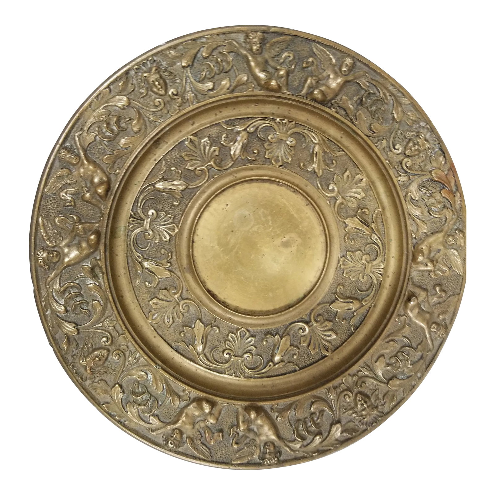 Mid 20th Century Brass Plate With Cherub Motif: Brass decorative plate featuring various floral designs and cherubs. There is pitting and a little bit of discoloration on the front and back, there is a part of the motif that seems to be discolored 