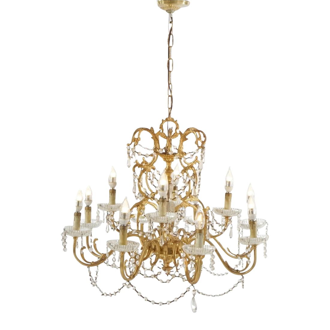French Style Gilt & Crystal Twelve-Light Tiered Chandelier, 1930: An antique French style chandelier offers a gilt frame with scrolled foliate arms terminating in twelve candle lights, strung and drop crystals throughout, c1930. Measures- 38''H x 26.5''W x 26.5''D; 