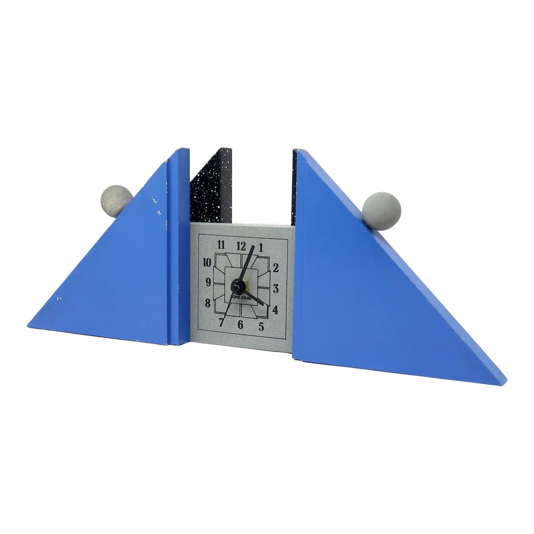 1980s French Postmodern Mantle Clock: A sculptural French postmodern mantel clock with blue and splatter painted supports, gray face and accents, and black numbers and hands. A fantastically contrasting low triangular shape with round det