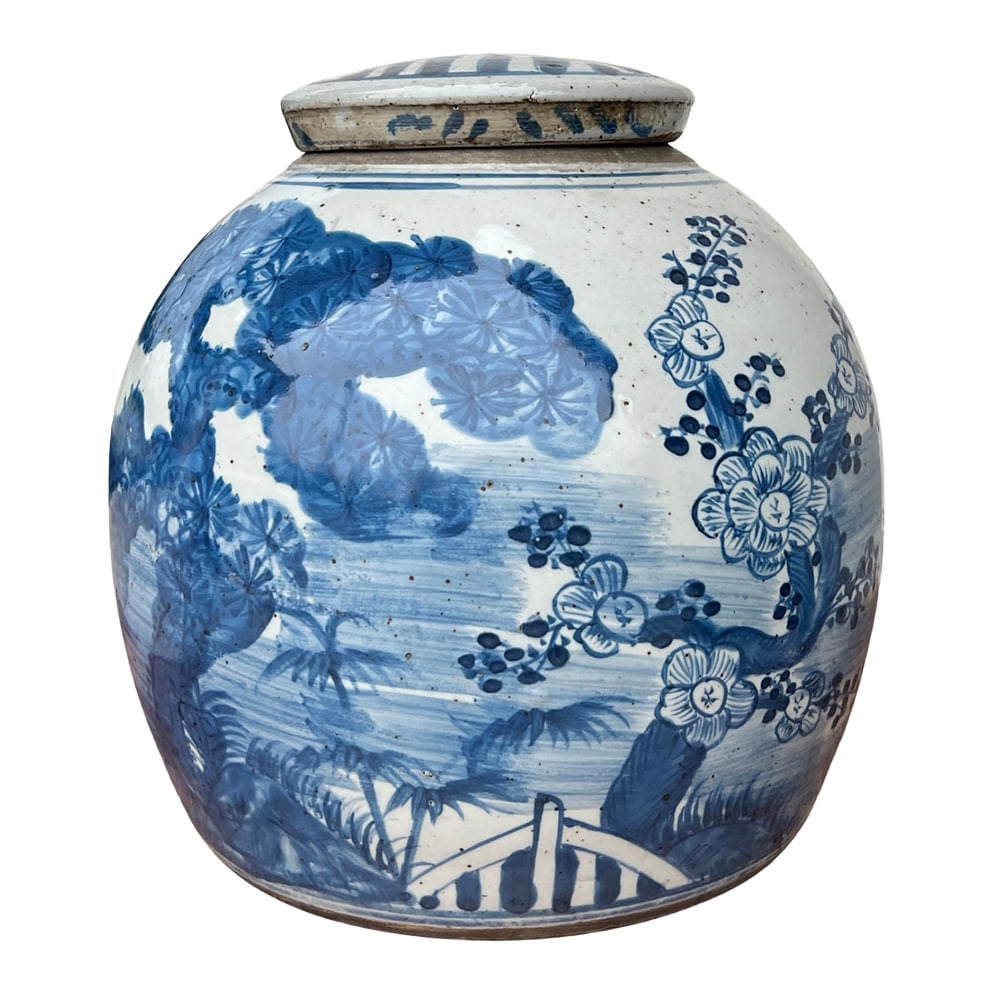 Chinoiserie Lidded Ginger Jar: This lidded ginger jar features a hand-painted blue and white landscape with blossoming trees, lush foliage, and a quaint arched bridge. Soft brushwork and subtle speckling in the glaze give it an ant