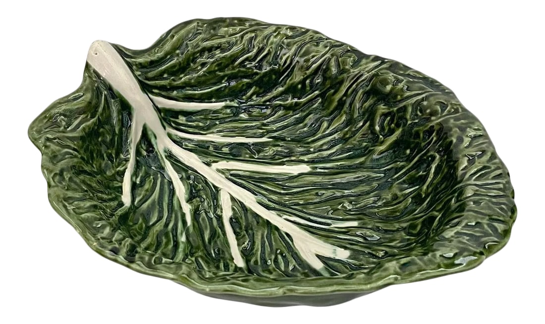 1960s Majolica Cabbage Leaf Serving Bowl: Vintage hand-made ceramic cabbage leaf serving bowl with glossy green majolica glaze. Made in Portugal. Bowl has chip on underside rim. Condition: Alterations: Original Condition Unaltered