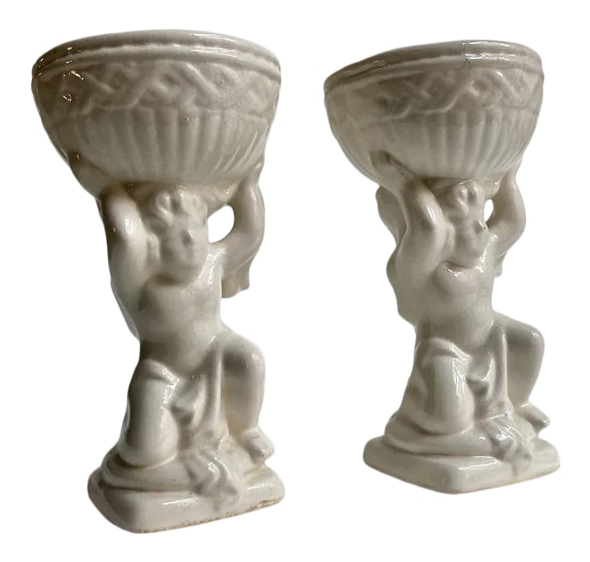 Mid 20th Century Cream Ceramic Cherub Vases Candle Holders - A Pair: Pair of draped and kneeling Off White Glazed Ceramic Putti's and holding adorned Bowls on balanced squat square base. Great as Planters. Dried Flower Arrangement Containers. Rooting Plant Containers.