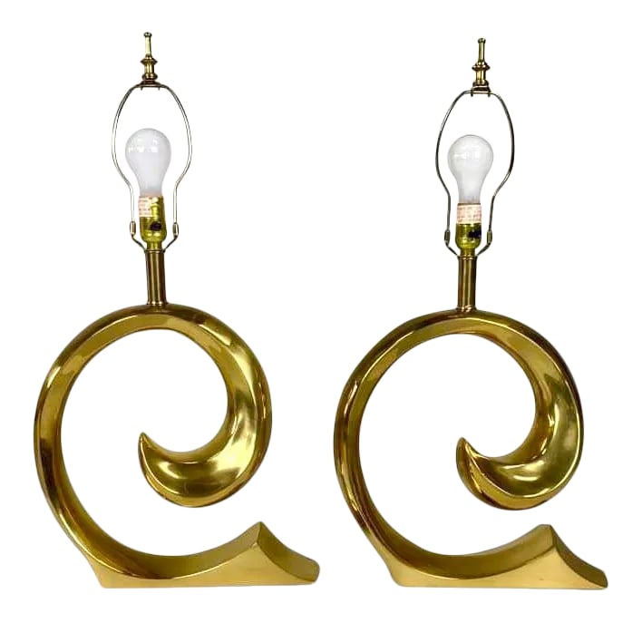 1970s Erwin Lambeth for Pierre Cardin Solid Brass Lamps - A Pair: An elegant and sculptural pair of brass lamps designed by Erwin Lambeth for Pierre Cardin. They are cast in the shape of a swoosh form that was also Cardin's logo. This pair is in excellent vintage
