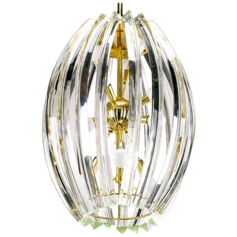 Bent Glass Rib & Brass Chandelier in the Manner of Venini: Bent Venini-style glass crystal "ribs" surround a brass finish metal "sputnik" style frame. Twelve sockets are attached to the center brass globe at various angles. Presently hung by a brass rod, but 