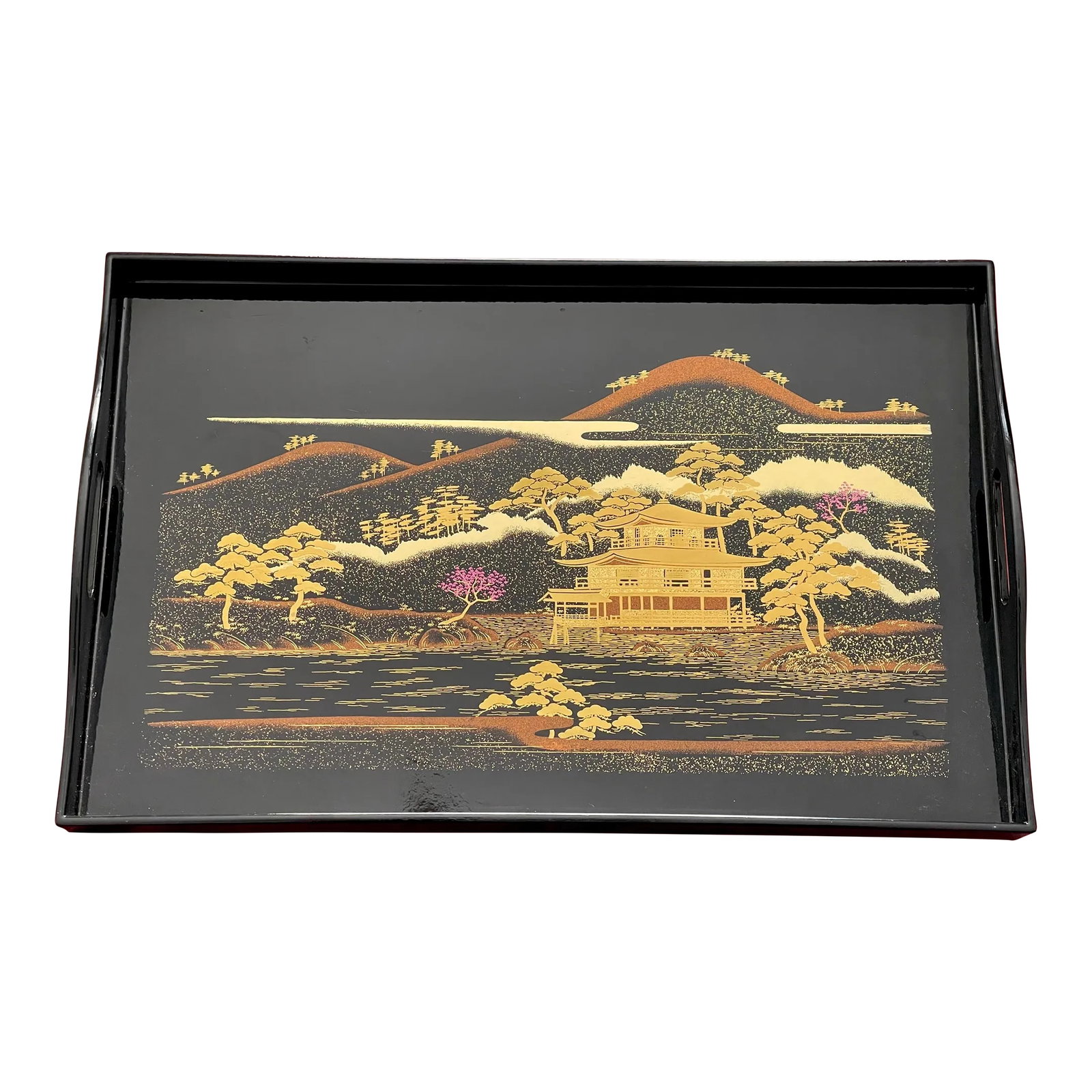Mid 20th Century Black & Gold Chinoiserie Serving Tray: A mid 20th century handled serving tray showing a stylized landscape of river and mountains in a warm color palette with pops of violet in the form of a pair of trees in bloom. A peaceful looking pago