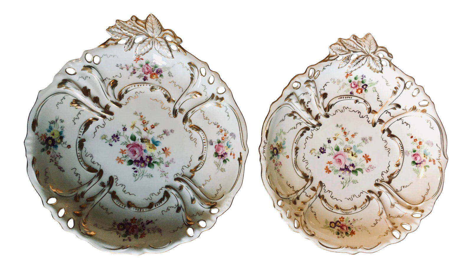 Rococo Pierced Edge Plates - Set of 2: Pair of Rococo French plates/bowls with swirling gold details and a leaf motif handle. Each is hand-painted with arrangements of flowers in bright, fresh colors. Dimensions: 10.25" x 9.43" x 1.25"